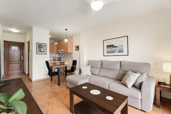 A modern living room with a sofa, a coffee table, and a dining area with chairs and a table.