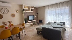 Una sala moderna con comedor, televisión y cama.