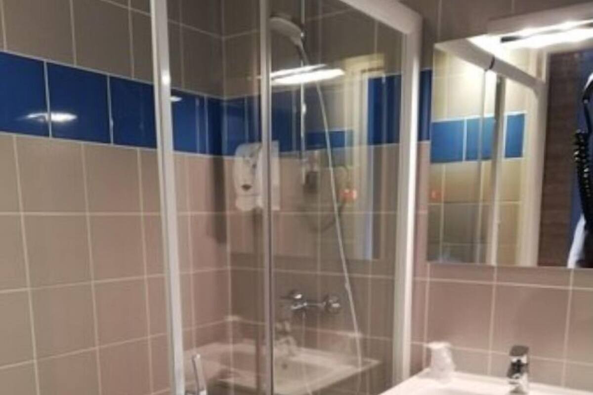 Un baño moderno con ducha de vidrio, un lavabo blanco y un espejo sobre el tocador.