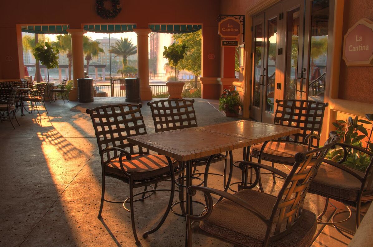 An outdoor patio with a table and chairs, a view of the street, and a sign reading "La Cantina".