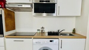 Eine kompakte Küche mit Einbauofen, Mikrowelle und einer Waschmaschine mit Frontlader.