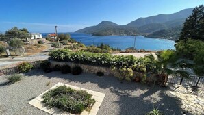 Un paysage côtier avec un sentier en pierre, un petit jardin et une vue sur la mer et les montagnes.