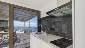 A modern kitchen with a large window, a built-in stove, and a view of the sea.