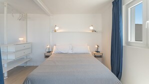 Une chambre à coucher avec un lit, des tables de chevet, une commode et une fenêtre avec des rideaux.