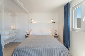 Une chambre à coucher avec un lit, des tables de chevet, une commode et une fenêtre avec des rideaux.