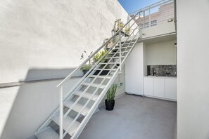 A white staircase with metal railings leading to a balcony, surrounded by a white wall and a potted plant. - 'El Palomar' with Shared Terrace and Wi-Fi (Santa Cruz)
