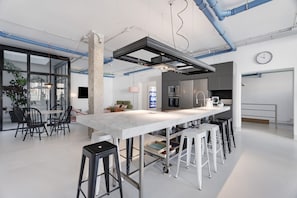 A modern kitchen with a central island, bar stools, and a dining area with chairs.
