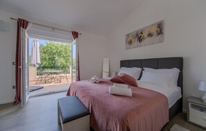 Ein Schlafzimmer mit Bett, Nachttisch und Blick auf einen Außenbereich mit Tisch und Stühlen.