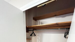 A walk-in closet with wooden shelves, a hanging rod, and a white door. - The Shaded Retreat (Louisville)