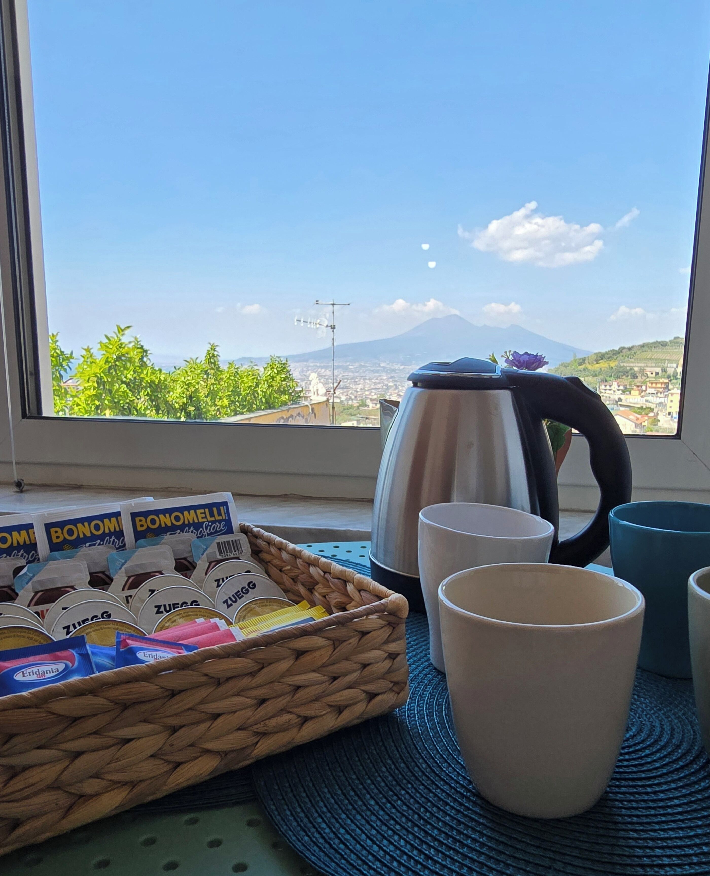 Un coin cuisine avec vue sur une montagne, une bouilloire et un panier contenant des produits alimentaires.