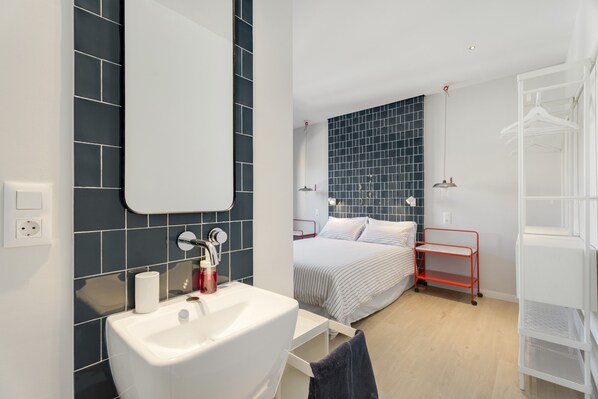 Ein modernes Badezimmer mit einem weißen Waschbecken, einem Spiegel und dunkelblauen Fliesenwänden.