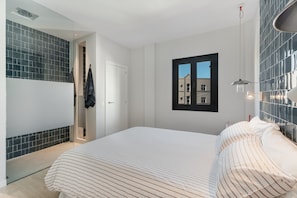 Un dormitorio con cama, ventana, puerta y pared con azulejos.