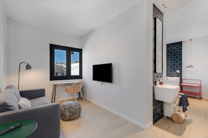 Ein modernes Wohnzimmer mit einer Couch, einem Fernseher, einem Schreibtisch und einem Sessel.