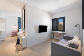 Una sala de estar moderna con televisor de pantalla plana, un sofá, una mesita y una ventana con persianas.
