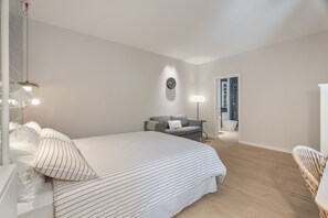 Un dormitorio con una cama grande, un sofá, una lámpara y un reloj en la pared.