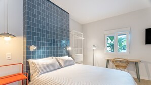 Ein Schlafzimmer mit Bett, Schreibtisch, Stuhl, Regal und Fernseher an der Wand.