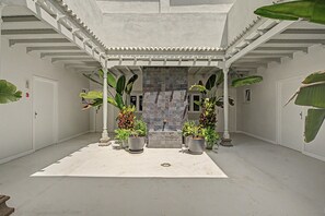 A covered courtyard with a tiled wall, potted plants, and a door marked with the number 3.