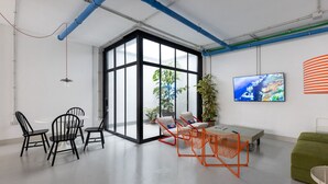 Ein moderner Arbeitsbereich mit einer großen Glastür, einem grünen Sofa und einem Fernseher an der Wand.