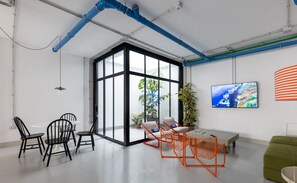 Ein moderner Arbeitsbereich mit einer großen Glastür, einem grünen Sofa und einem Fernseher an der Wand.