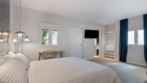 A bedroom with a bed, a desk, a chair, a TV, and a closet.