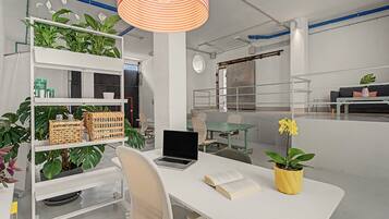 Un espacio de oficina moderno con muebles blancos, un escritorio con una computadora portátil, una estantería con plantas y una planta en maceta amarilla sobre el escritorio.