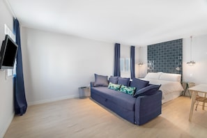 A modern living room with a sofa, a TV, a small table, and a bed with a blue-tiled headboard. - Suite Pescado Salado 7 with Shared Terrace and Wi-Fi (Santa Cruz)