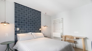 A bedroom with a bed, bedside tables, a desk, and a chair.