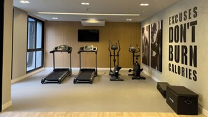 Un gimnasio con cintas de correr, elípticas y una pared con mensajes motivacionales.