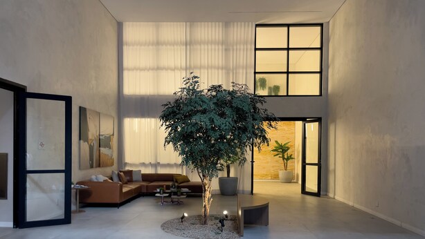 Amplia sala de estar con un sofá seccional grande, una mesa de centro y un árbol en el centro.