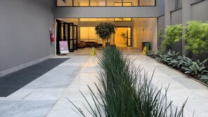 Un moderno vestíbulo de hotel con entrada de vidrio, una zona de estar y una planta en maceta.