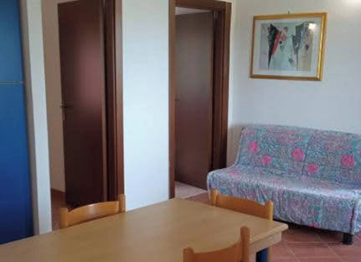 Una habitación con una mesa de madera, un sofá estampado y un cuadro en la pared.