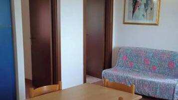 Una habitación con una mesa de madera, un sofá estampado y un cuadro en la pared.