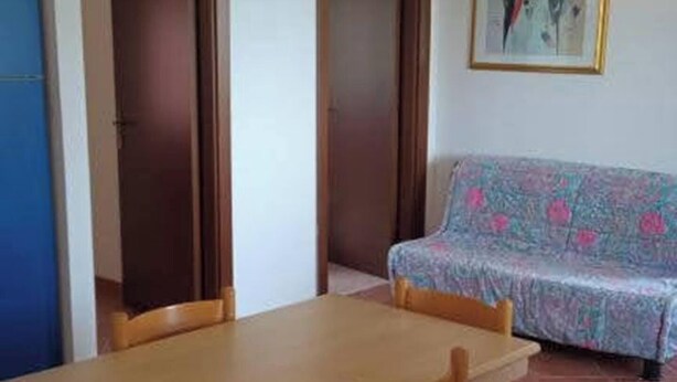 Um quarto com uma mesa de madeira, um sofá estampado e uma moldura na parede.