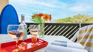 A terrace with a table set for two, featuring wine glasses, a bottle, and a vase with flowers.