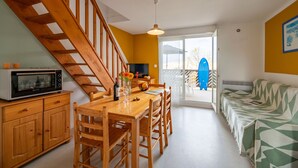 A kitchen with wooden cabinets, a dining table, and chairs. There is a staircase leading to another level.