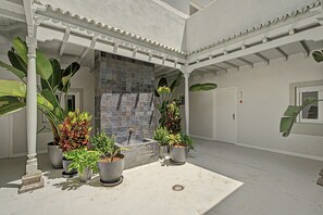 A covered outdoor area with potted plants and a tiled wall.