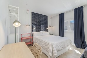 A modern bedroom with a bed, bedside tables, a hanging light fixture, a wardrobe, and a window with curtains.