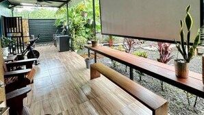 An outdoor patio with wooden benches, a large screen, and potted plants.