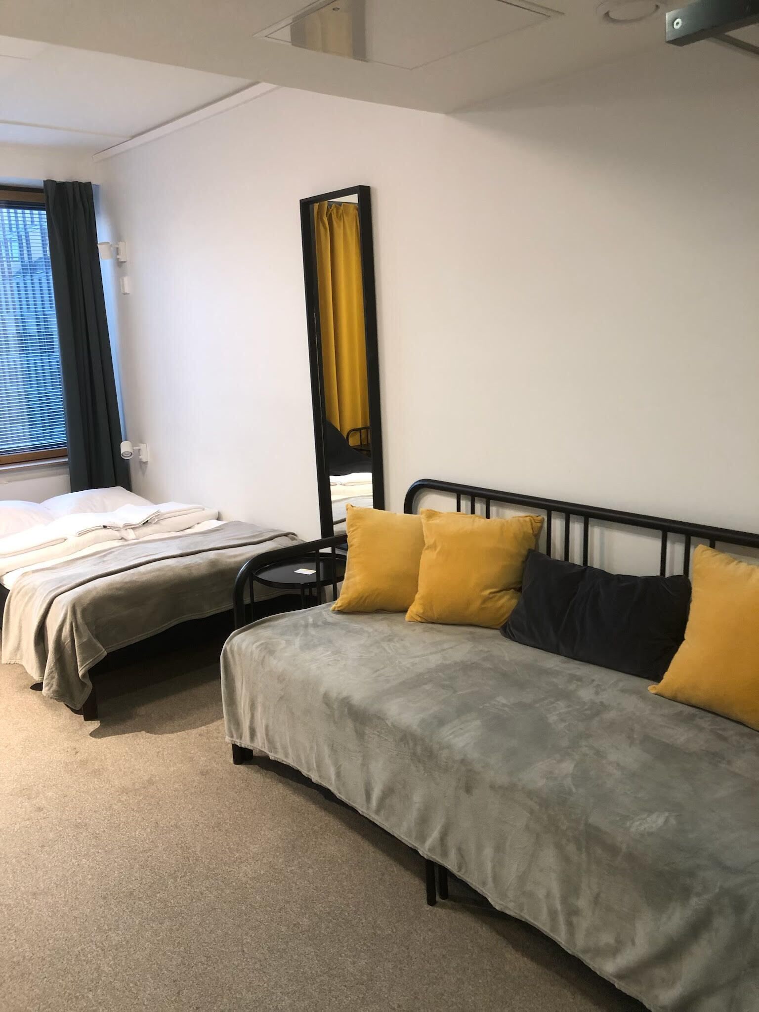 Une chambre d’hôtel avec deux lits, un grand miroir et une vue sur l’extérieur.