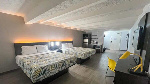 A hotel room with two beds, a desk, a chair, and a kitchenette. - Studio 6 Rockford, IL – RFD Airport (Rockford)