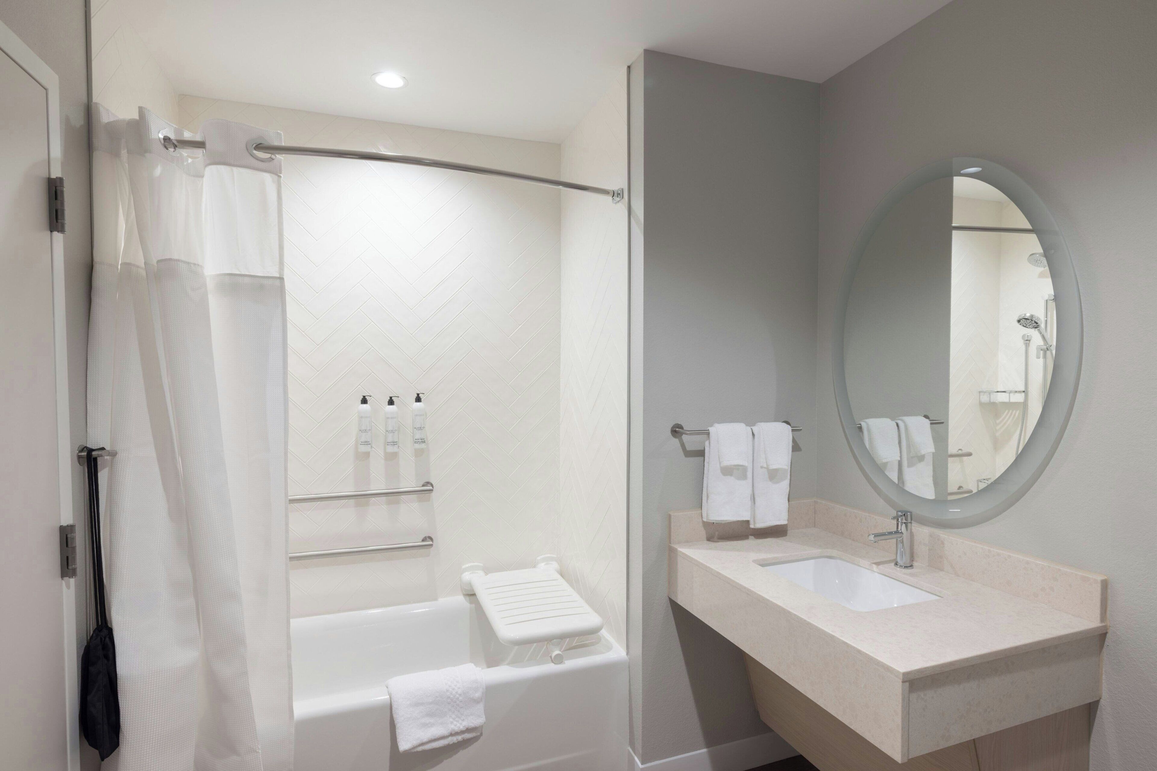 Un baño moderno con bañera, ducha, lavabo y espejo.
