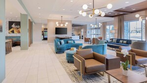 A modern hotel lobby with a large seating area, a flat-screen TV, and a large window offering a view of the city. - Towneplace Suites By Marriott Dayton Beavercreek (Beavercreek)