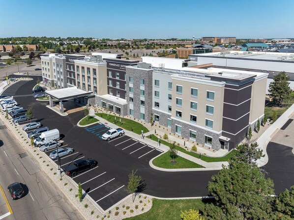 A multi-story hotel with a parking lot, a central courtyard, and a view of the surrounding area.