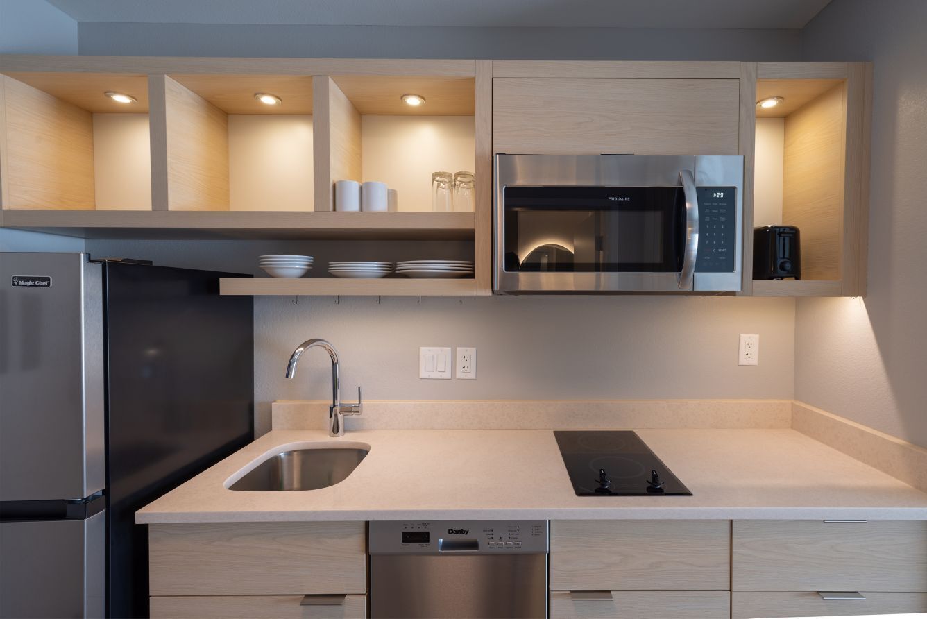 A modern kitchen with a built-in microwave, stainless steel refrigerator, and a dishwasher.