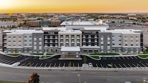 A multi-story hotel with a modern design, featuring a central courtyard and a parking lot in front. - Towneplace Suites By Marriott Dayton Beavercreek (Beavercreek)