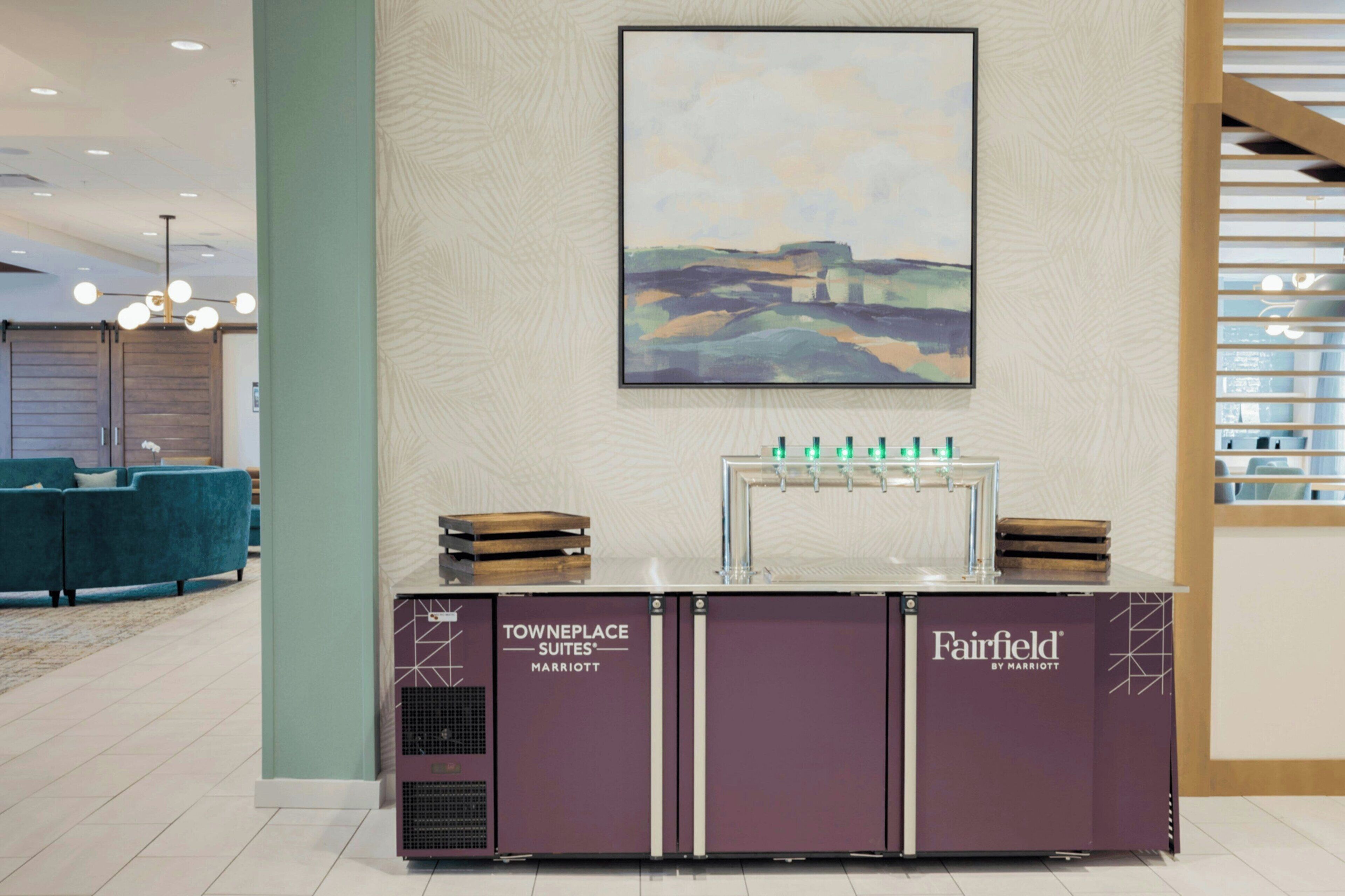 Een receptiegedeelte met een TOWNEPLACE SUITES® bord, een Fairfield by Marriott bord en een schilderij aan de muur.