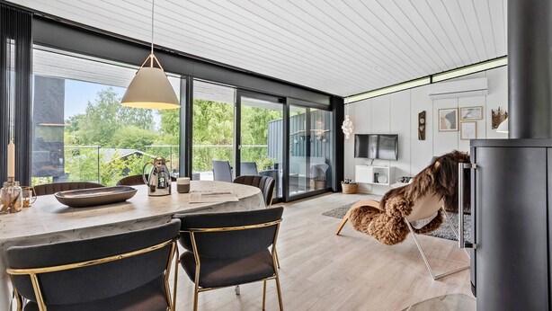 Una cocina moderna con una isla grande, un comedor con sillas, un perro y un televisor.