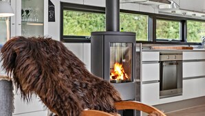 Una cocina moderna con estufa de leña, armarios blancos y vistas al exterior.