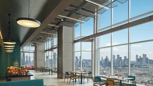 A spacious dining area with high ceilings, large windows, and a city view.