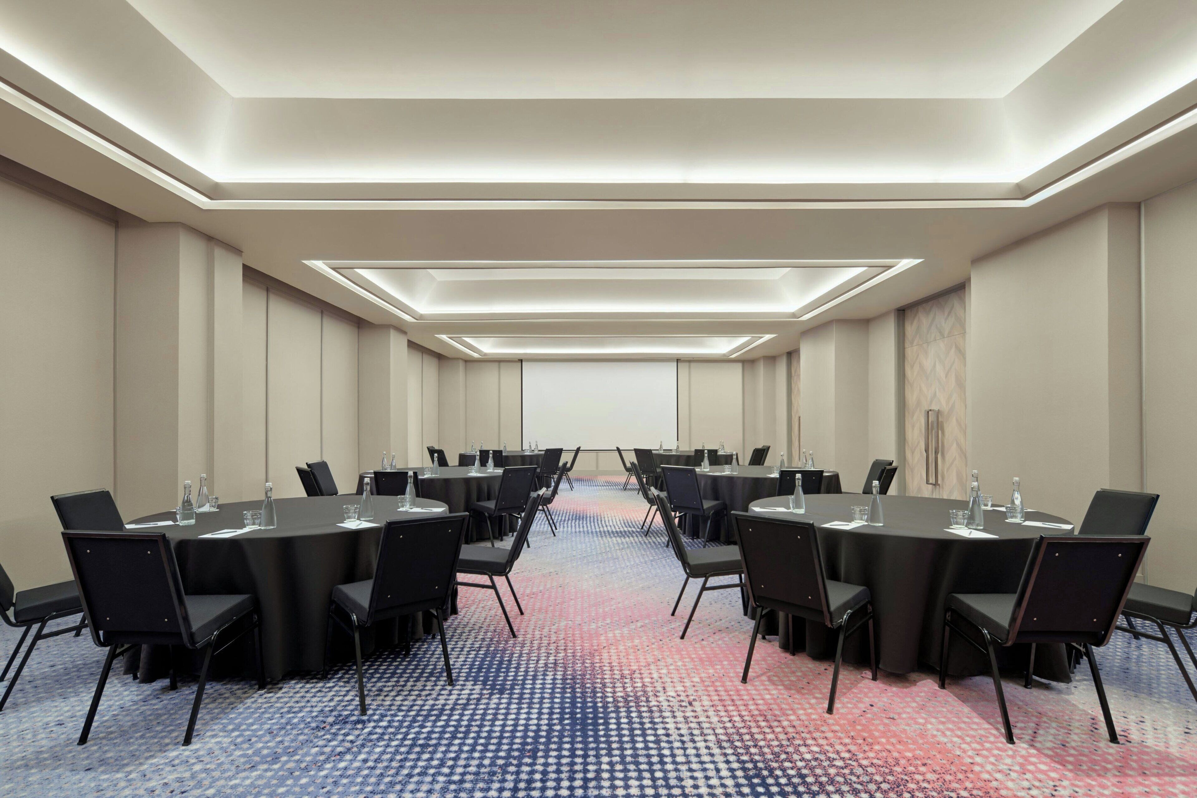 A conference room with a long table, black chairs, and a patterned carpet.